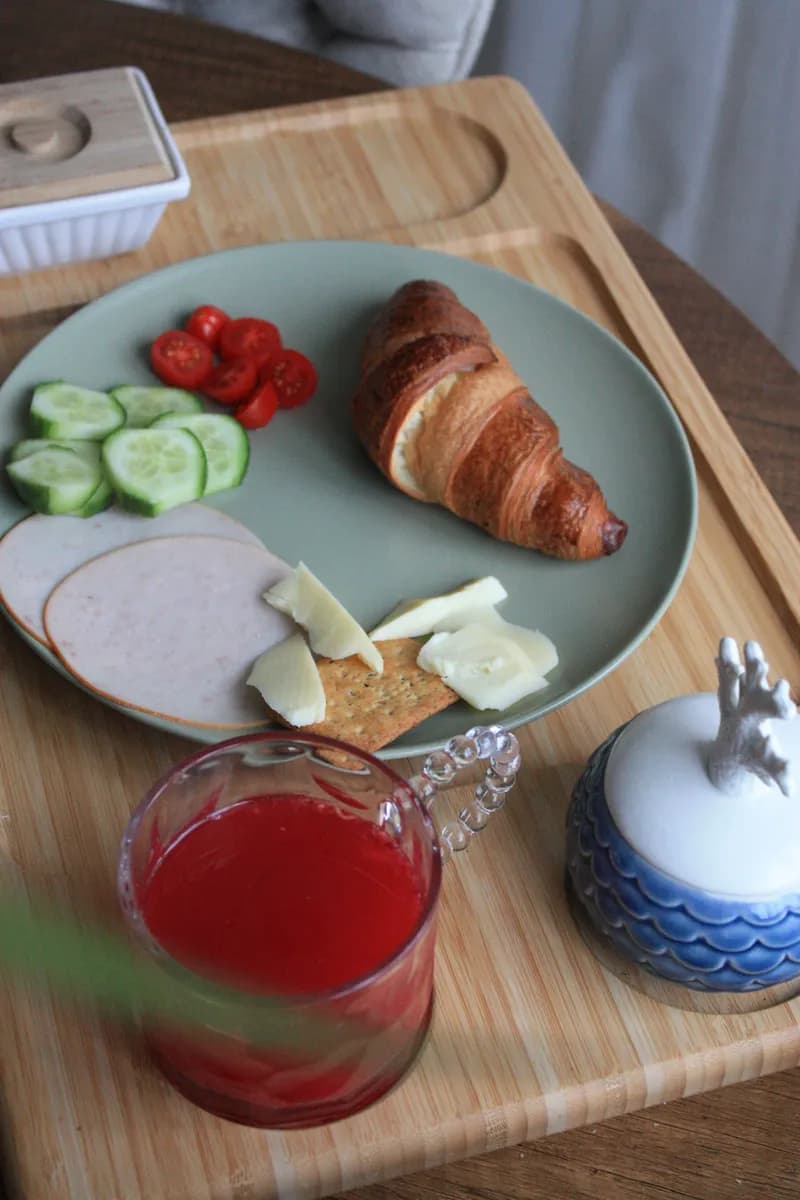 BookNoFees example image: Breakfast tray with a croissant, vegetables and juice