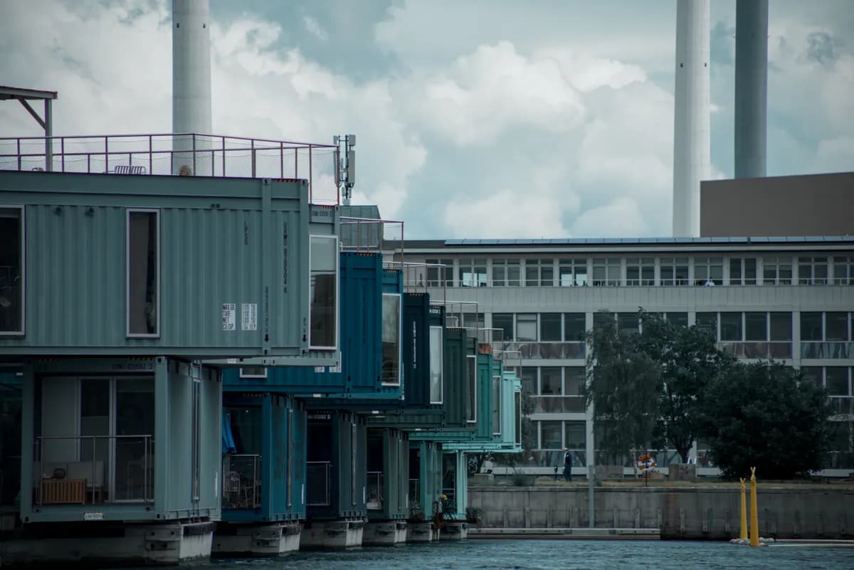 BookNoFees example image: Colourful container homes with a jetty by the water