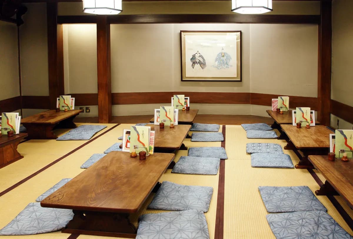 BookNoFees example image: Japanese dining room with low wooden tables and seat cushions on tatami mats