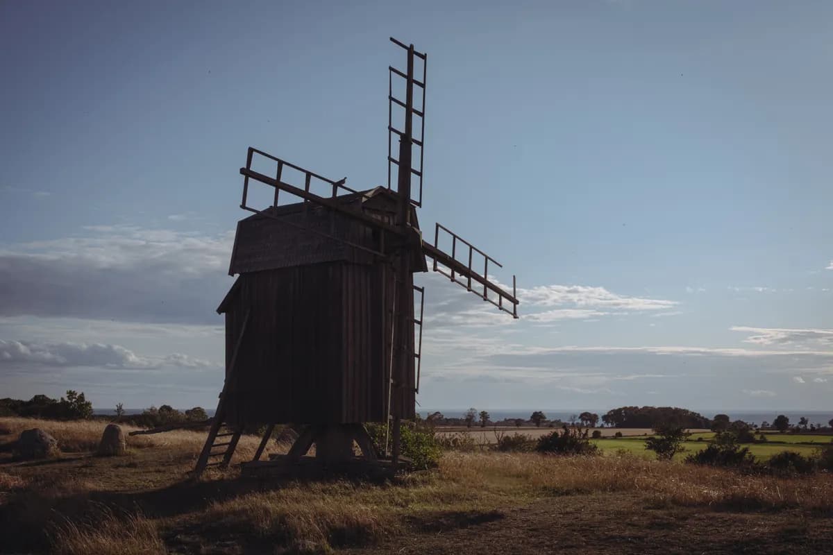 BookNoFees example image: Wooden windmill with sails in an open landscape