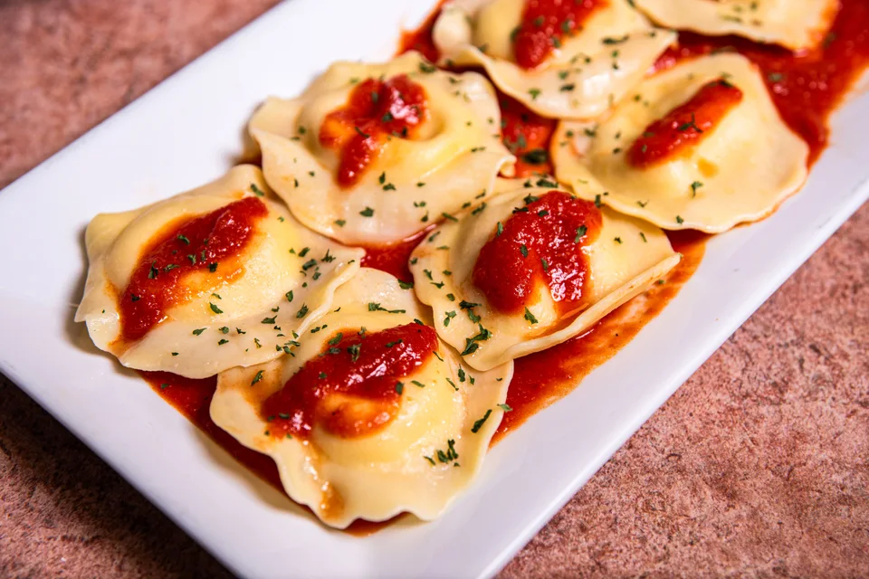 BookNoFees: Example photo: Ravioli topped with tomato sauce and herbs on a white plate
