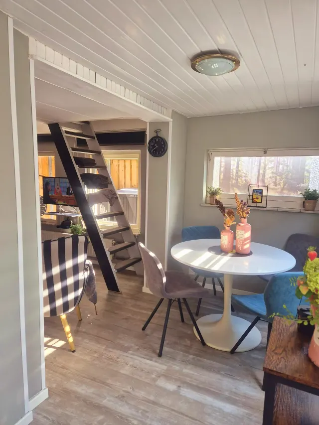 BookNoFees holiday home in Domburg, Zeeland, Netherlands – Dining area with round table, blue chairs, and slanted wooden ceiling