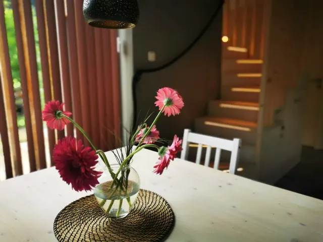 BookNoFees holiday home in Hieflau, Styria, Austria – Dining area with white table, vase of pink flowers, and wooden staircase