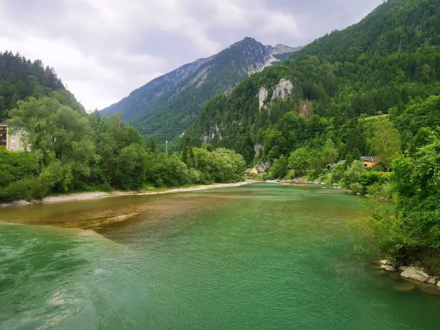 BookNoFees holiday home in Hieflau, Styria, Austria – River view with forested mountains and a yellow house on the shore