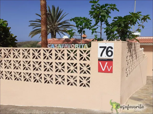 BookNoFees holiday home in Buen Paso, Tenerife, Spain – Exterior wall with decorative concrete blocks, house number 76, and palm trees behind