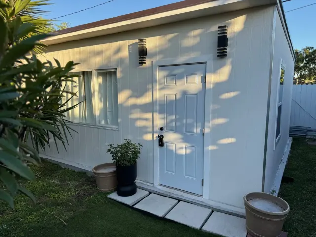 BookNoFees holiday home in Cutler Bay, United States – Exterior of white tiny house with front door, potted plants, and stone path