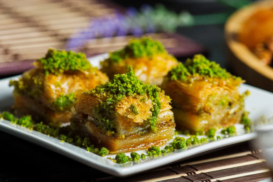 BookNoFees: Example photo: Four pieces of layered baklava topped with crushed pistachios on a white plate